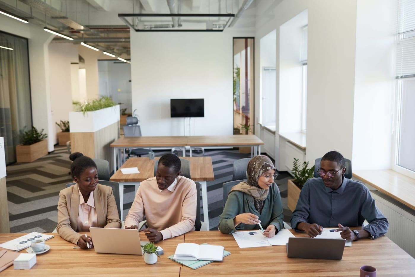 Quattro colleghi di eta’ e origini diverse lavorano insieme intorno a un tavolo.